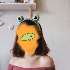 a woman with her face painted to look like a green frog wearing a headband