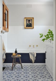 a blue and white tiled bathroom with a painting on the wall above the bathtub