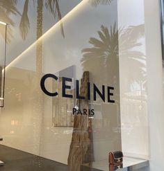 a store front window with palm trees reflected in it's glass door and the word, celline paris