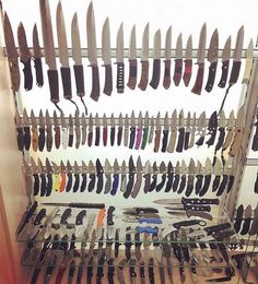 many knives are hanging on the wall in front of a display case with several different types of knives