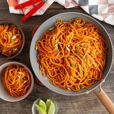 three bowls filled with spaghetti on top of a wooden table next to utensils