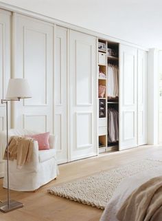 a bedroom with white closets and a bed in the corner next to a chair