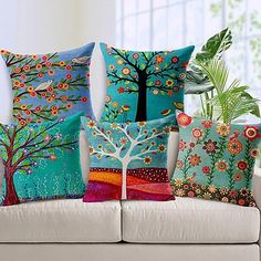 four colorful pillows on a white couch in front of a window with potted plants