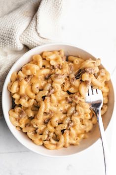 a white bowl filled with macaroni and cheese on top of a marble counter