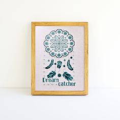 a cross - stitch pattern in a wooden frame with the words dream catcher on it