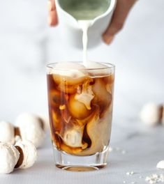 a person pouring ice into a glass filled with liquid