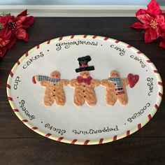 three gingerbread men on a plate with poinsettis