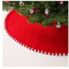 a christmas tree skirt with ornaments on it and a red rug under the tree in front