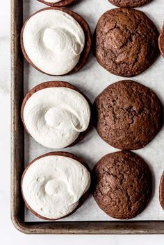 chocolate cookies with white frosting on a baking sheet