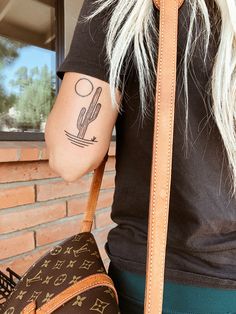 a woman with a tattoo on her arm holding a brown louis vuitton bag