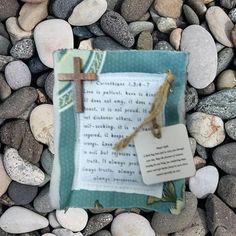 a book with a cross on it laying on some rocks next to a paper tag