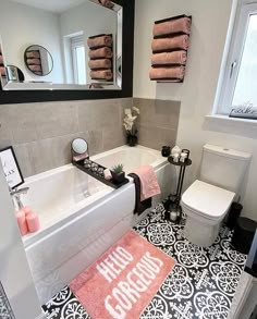 a bathroom with black and white tile flooring and pink towels on the bathtub