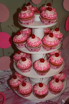 there are cupcakes on the three tiered cake stand with cherries in them