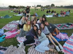 a group of young women sitting on top of a lush green field next to each other