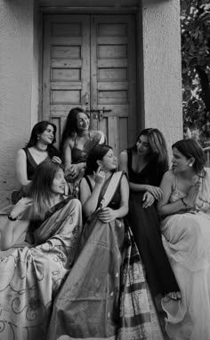 black and white photograph of four women sitting on the steps in front of a door