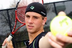 a young man holding a tennis ball and racquet