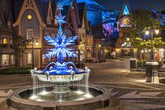 an illuminated fountain in the middle of a street