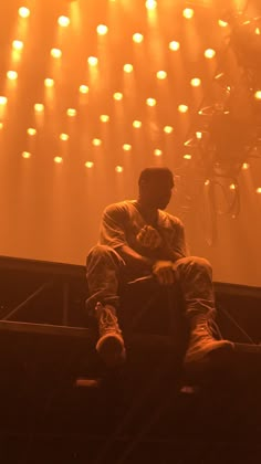 a man sitting on top of a stage with his feet up in front of him