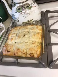 a pan filled with food sitting on top of a stove next to a tea pot