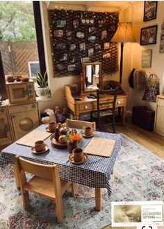 a table with tea cups and plates on it in front of a wall full of pictures