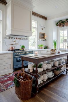 a kitchen island with plates and bowls on it in the middle of a wooden floor