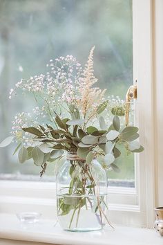 a vase filled with flowers sitting on top of a window sill