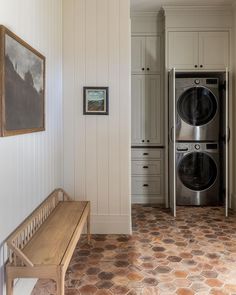 a washer and dryer in a white room with brown tile on the floor