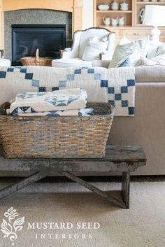 a basket sitting on top of a wooden bench in front of a couch and fireplace