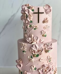 a pink cake with flowers and a cross on top