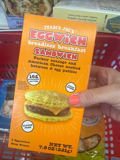 a person holding up a box of eggwich sandwich in front of some other items