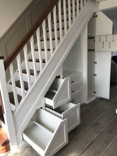 an open drawer under the stairs in a room with wood flooring and white walls