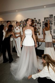 a woman in a white dress standing next to other women