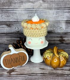 there is a small cake on top of a stand with pumpkins next to it