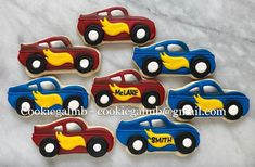 decorated cookies in the shape of cars with name on them, sitting on a marble surface