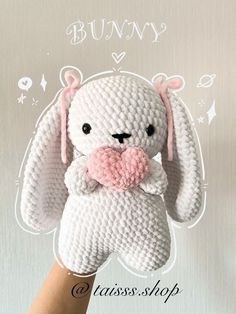 a hand holding up a white crocheted bunny with a pink heart in its mouth