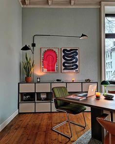 a room with a table, chairs and pictures on the wall next to a window