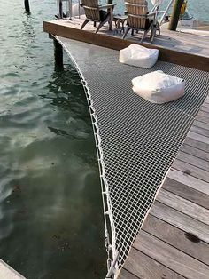 two chairs are sitting on the dock next to the water and one chair is empty