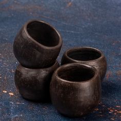 three black vases sitting on top of a blue surface