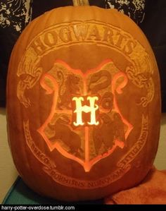 an orange carved pumpkin with the hogwarts crest on it's front and side