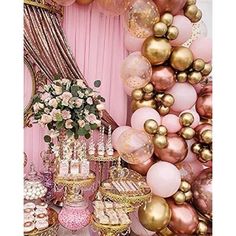 a table filled with lots of desserts and balloons in front of a pink wall