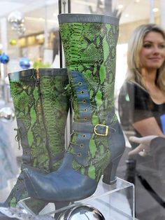 a pair of green boots sitting on top of a glass shelf next to a clock