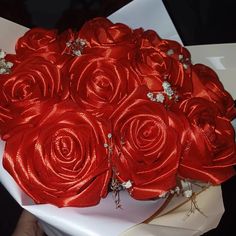 a bouquet of red roses wrapped in satin ribbon