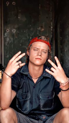 a young man sitting on the ground with his hands in the air and wearing a bandanna around his head