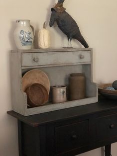 an old dresser with some items on top and a bird figurine above it