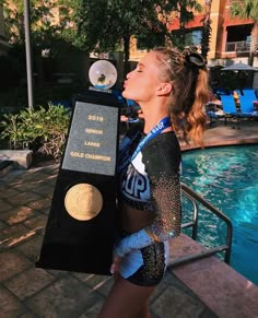 a woman holding a trophy next to a swimming pool