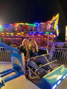 two women sitting on a carnival ride at night