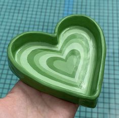 a hand holding a green heart shaped dish