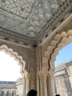 two people are standing under an intricately decorated ceiling in a building with arches and pillars