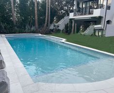 an empty swimming pool in front of a large house with stairs leading up to it