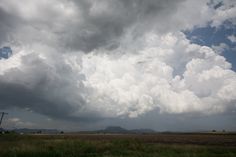 the sky is filled with clouds and green grass